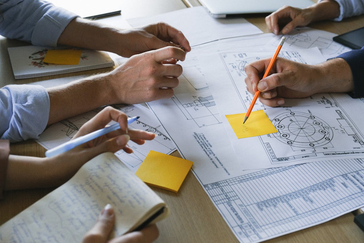 Close-up of hands working on business plans with sticky notes and drawings in an office.